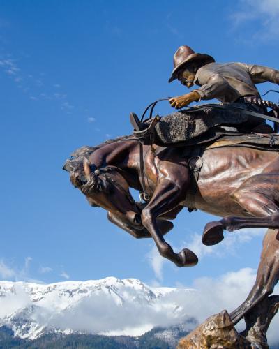 Bronze bronc rider sculpture in Joseph, Oregon, with the Wallowa Mountains behind
