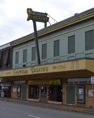 The image shows a street-level view of a building with a marquee that reads "Egyptian Theatre," situated on a street corner with other adjacent storefronts.