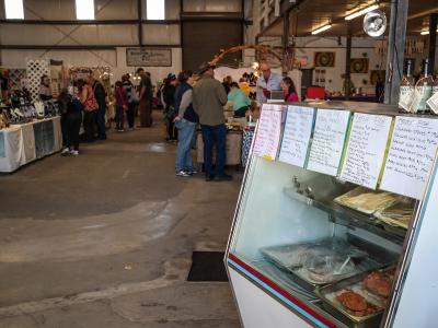The image shows the interior of a large warehouse-style market with vendors, shoppers, and a seafood display case in the foreground.